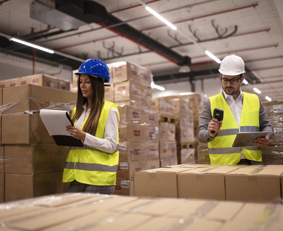 Warehouse Workers Using Bar Code Scanner Tablet Checking Goods Inventory
